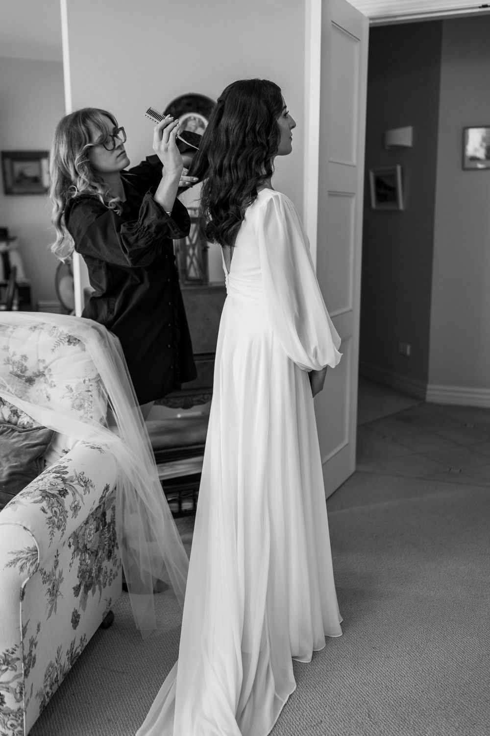 Black and white photos showing people preparing in a room with a white wedding dress visible.