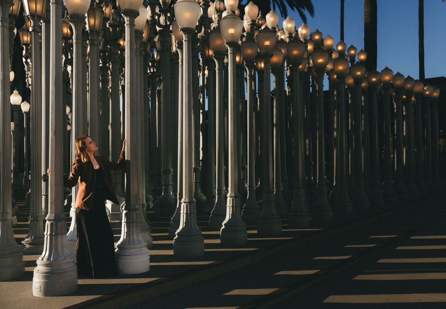 Rows of white columns create dramatic shadows and perspective in an urban art installation at dusk.