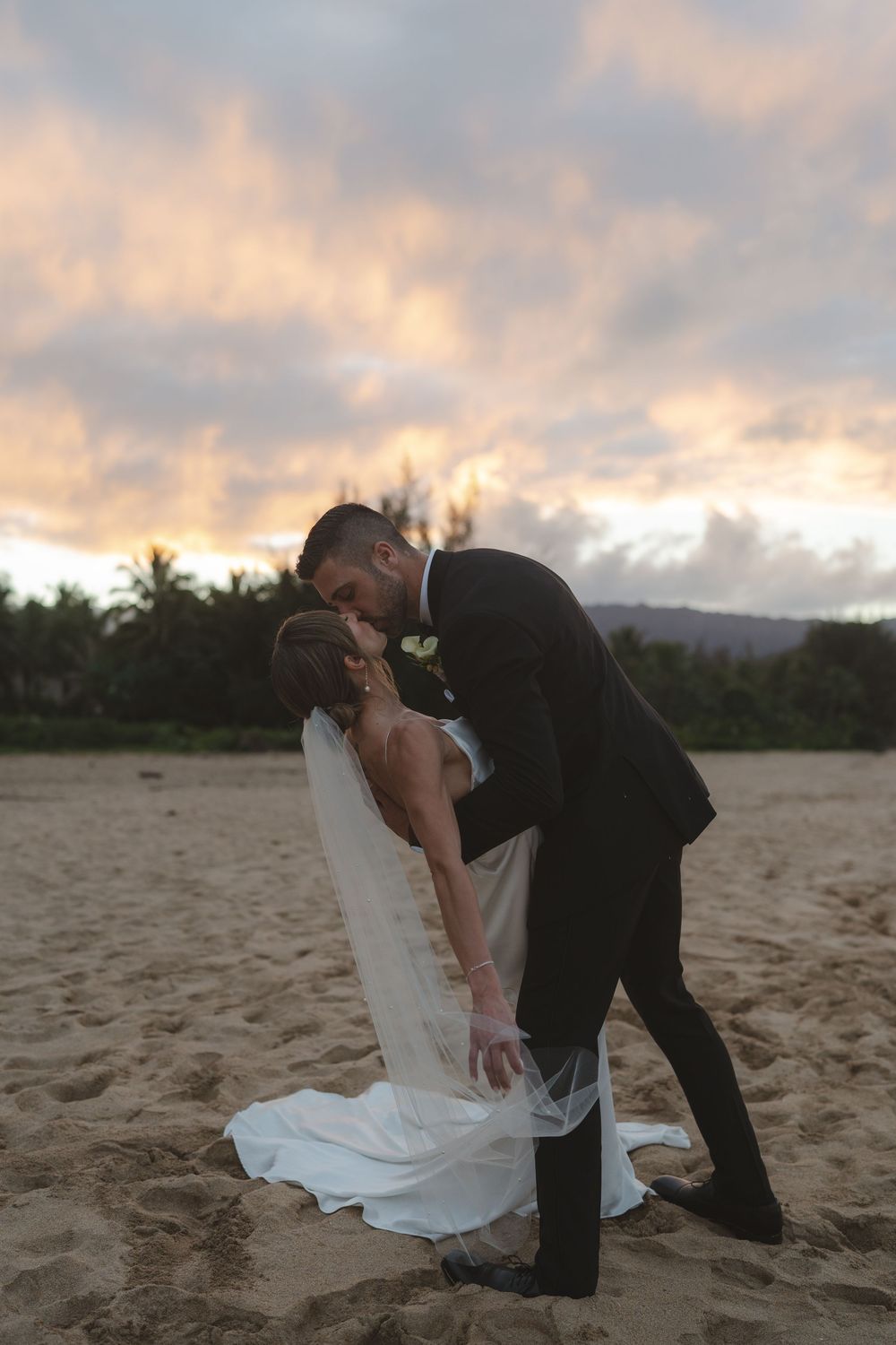 Bride and groom kissing at sunset at Hanalei Bay