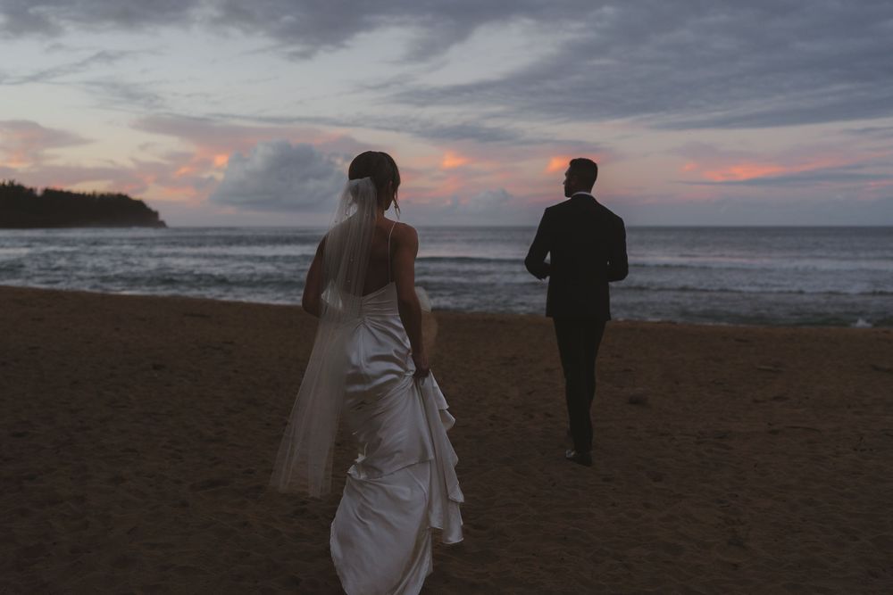 Bride and groom walking amongst the sunset in Hanalei Bay