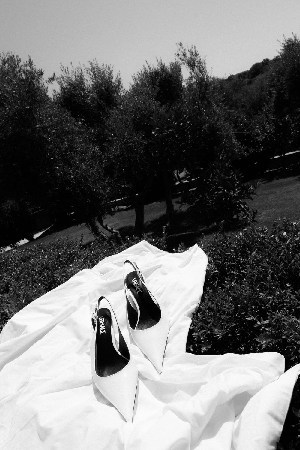 White bridal heels on wedding dress in black and white garden photo.