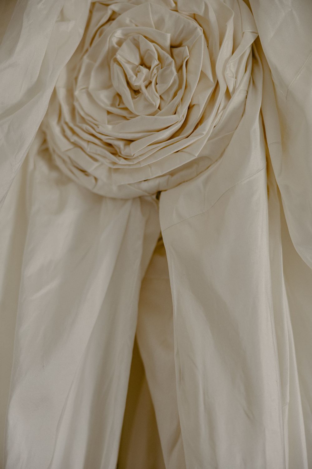 Close-up of an ivory wedding dress with an elegant fabric rose detail on the bodice.