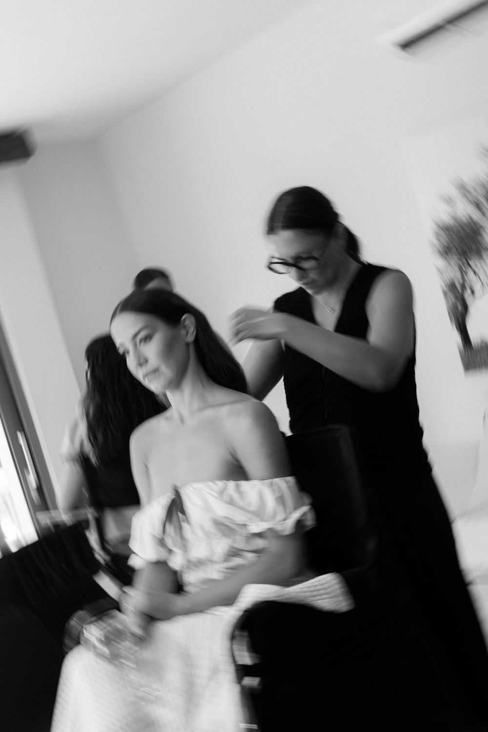 Black and white photo of a bride getting her hair styled by a hairdresser before the wedding.