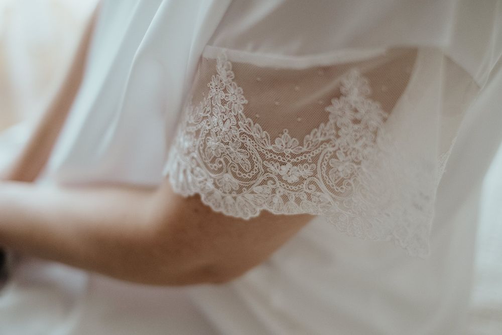 Close-up of intricate lace detailing on a white bridal wedding dress sleeve.