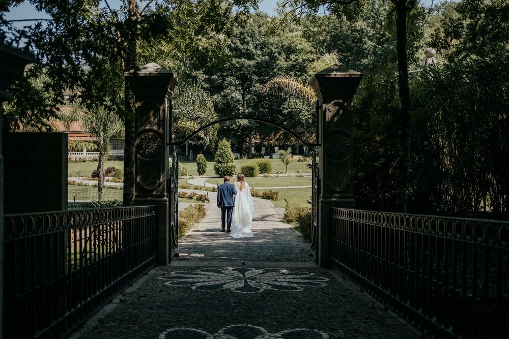 Bride and groom walking hand in hand through elegant garden gates on their wedding day.