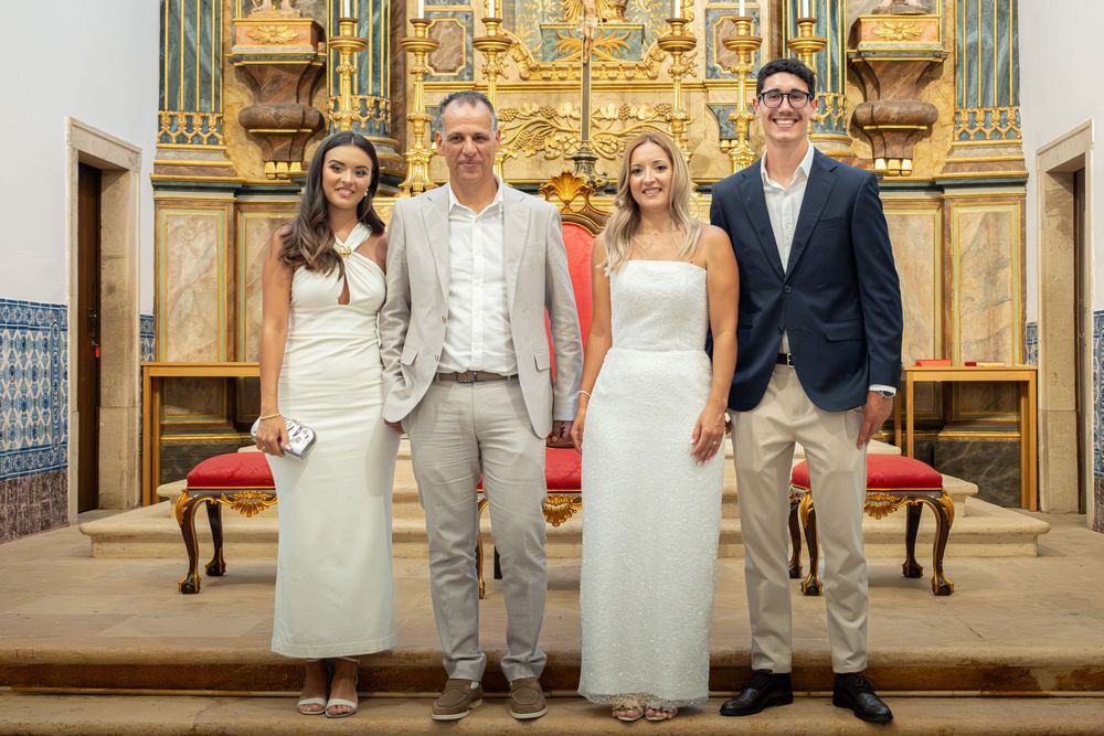 Four elegantly dressed people posing together inside an ornate church with golden altar backdrop.