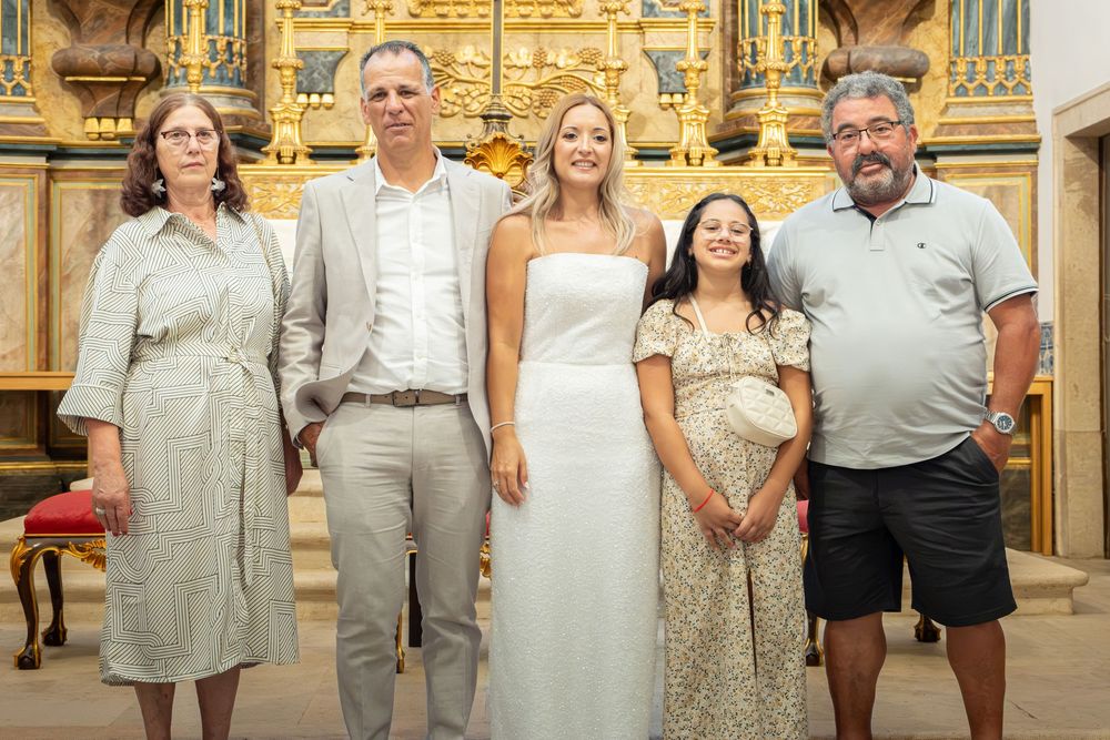 Family group photo inside an ornate church with golden altar, celebrating a wedding or special occasion.
