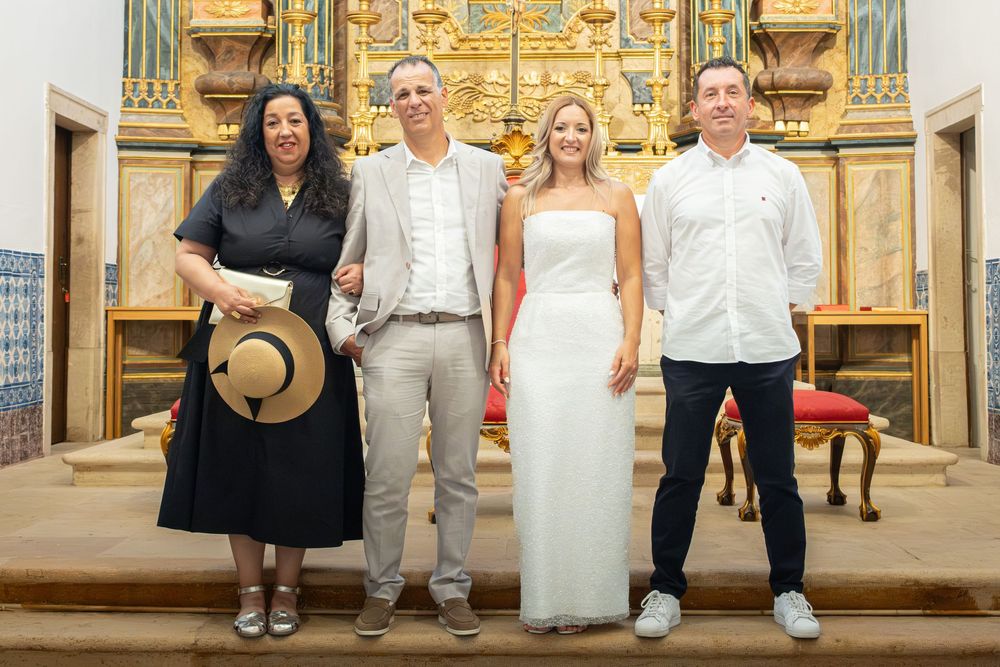 Four people posing together inside an ornate church with a golden altar, dressed in formal and semi-formal attire.