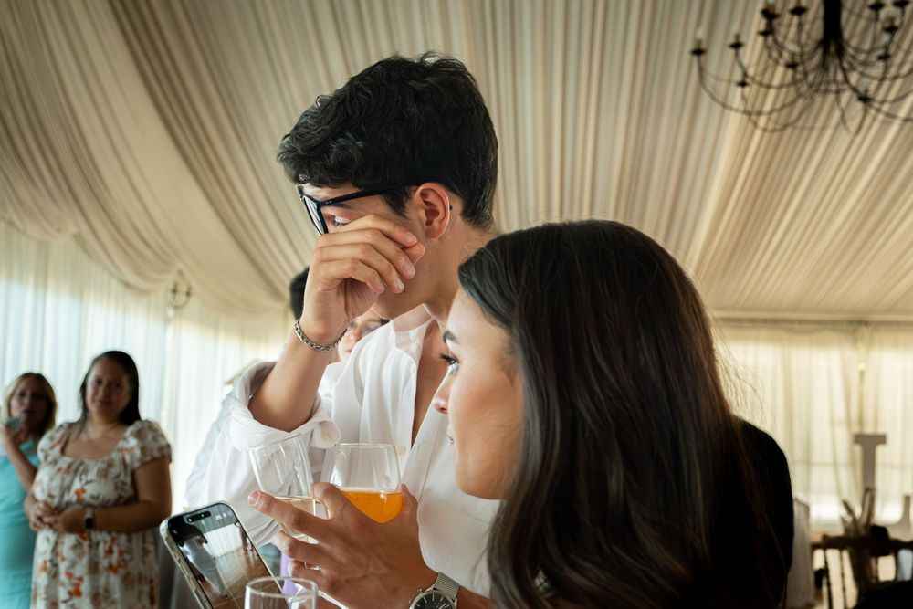 A young couple sharing a private moment at an elegant wedding reception under a white marquee tent.