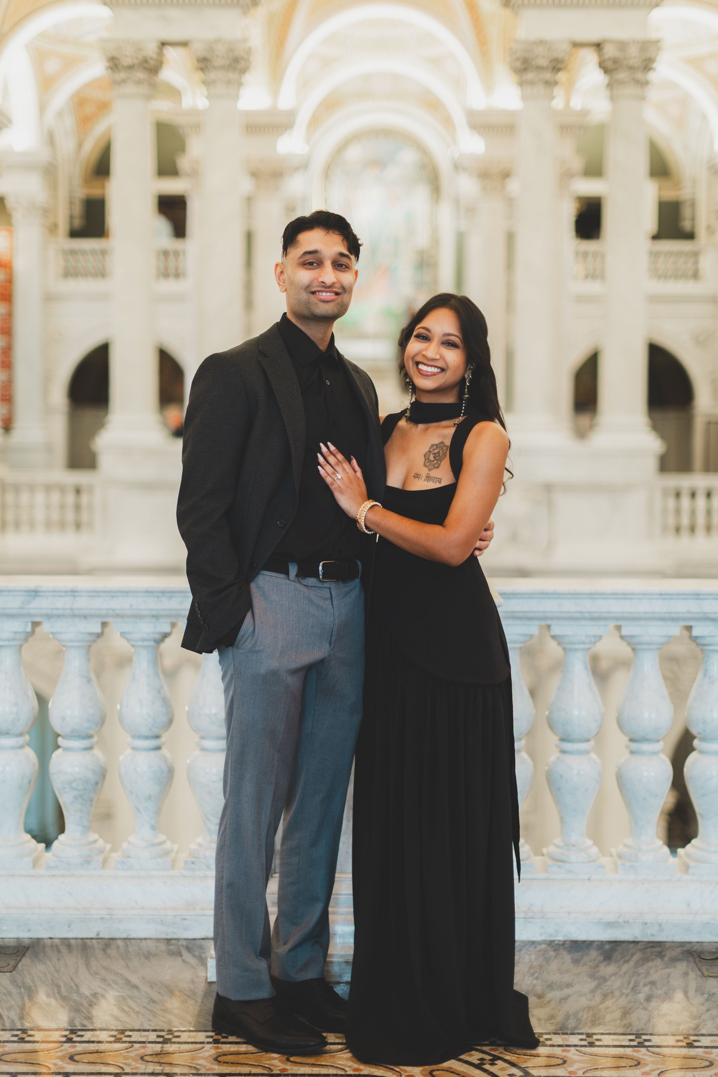 Couple in elegant black formal attire posing together at a grand marble balcony for a library of congress photography session