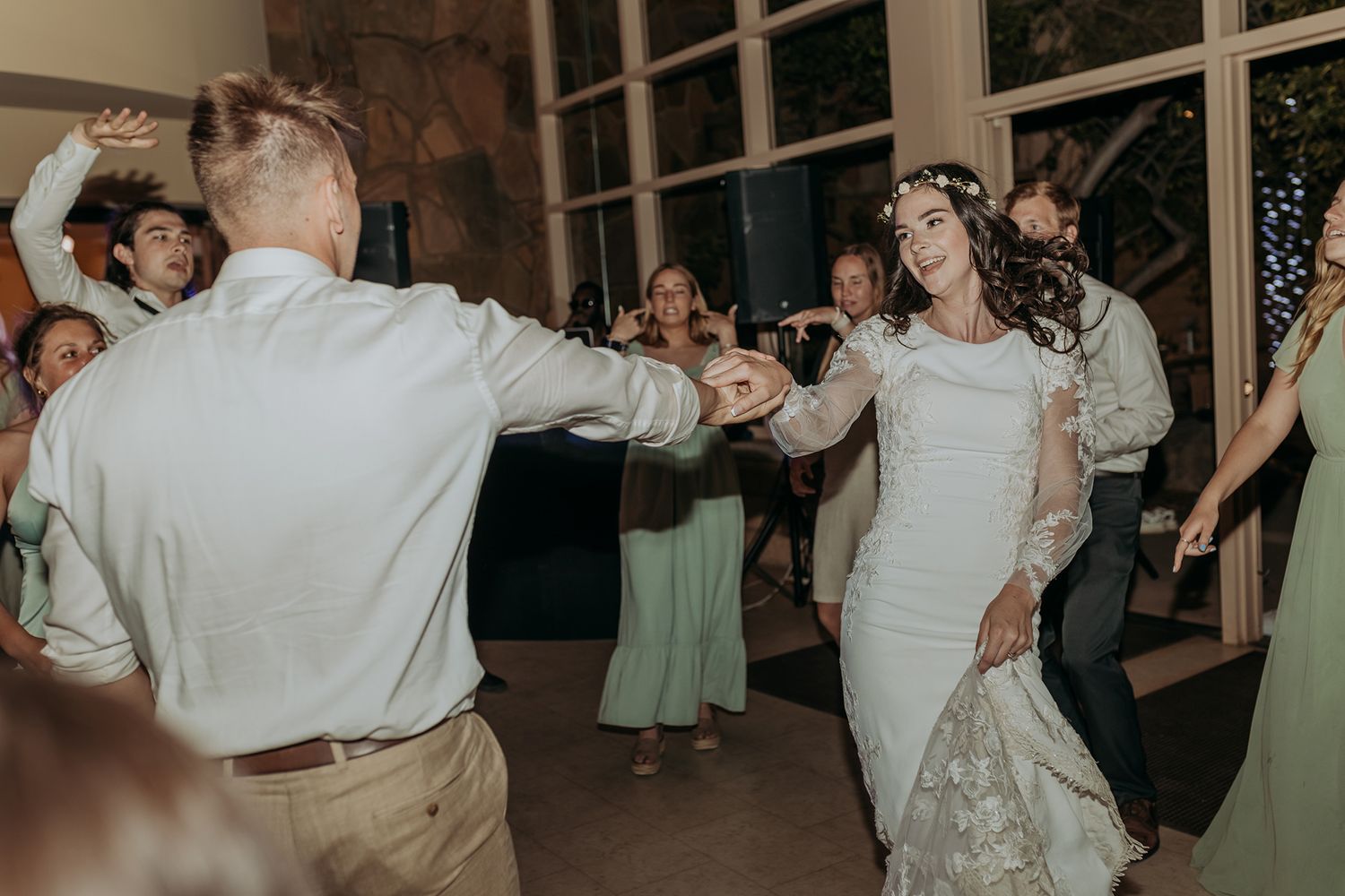 Bride and groom dancing joyfully at wedding reception with guests celebrating in background at Mission Trails Community Center.