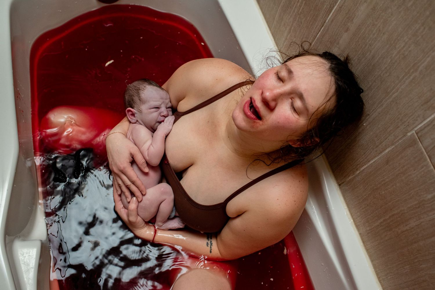A newborn baby and parent share a tender moment in a hospital delivery room.