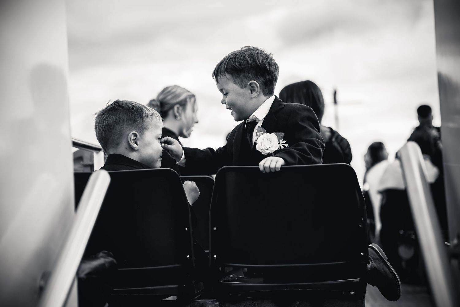 Black and white photo of children in formal attire laughing together at a wedding ceremony.