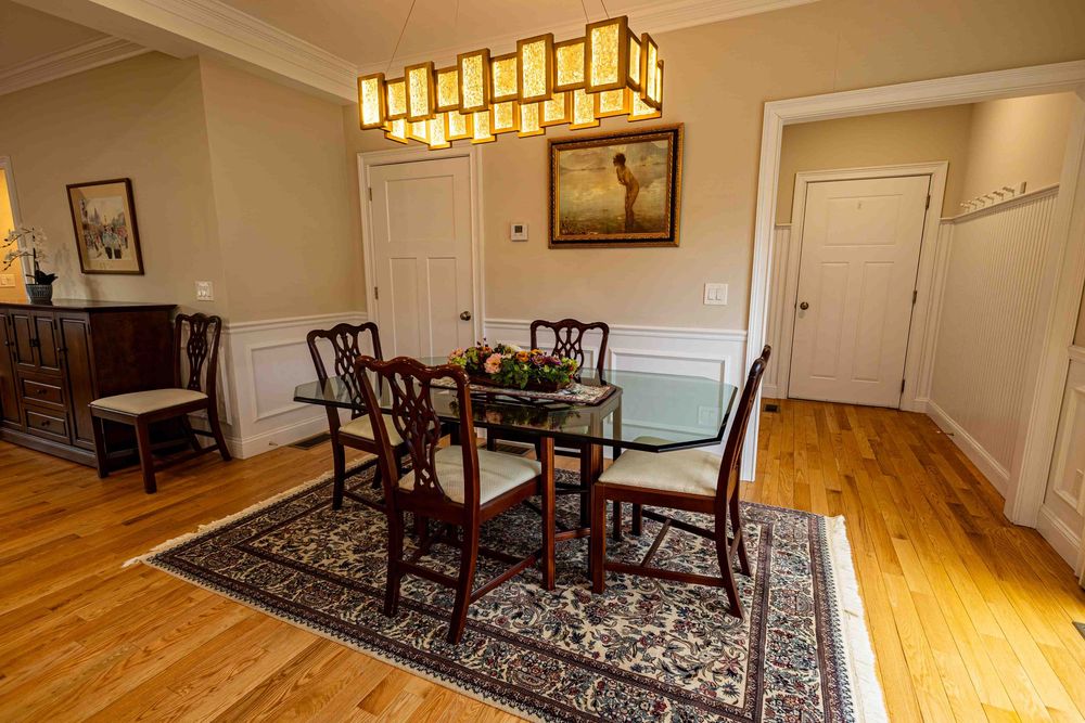 Elegant dining room featuring dark wood table, Chippendale chairs, oriental rug, wainscoting, and hardwood floors.