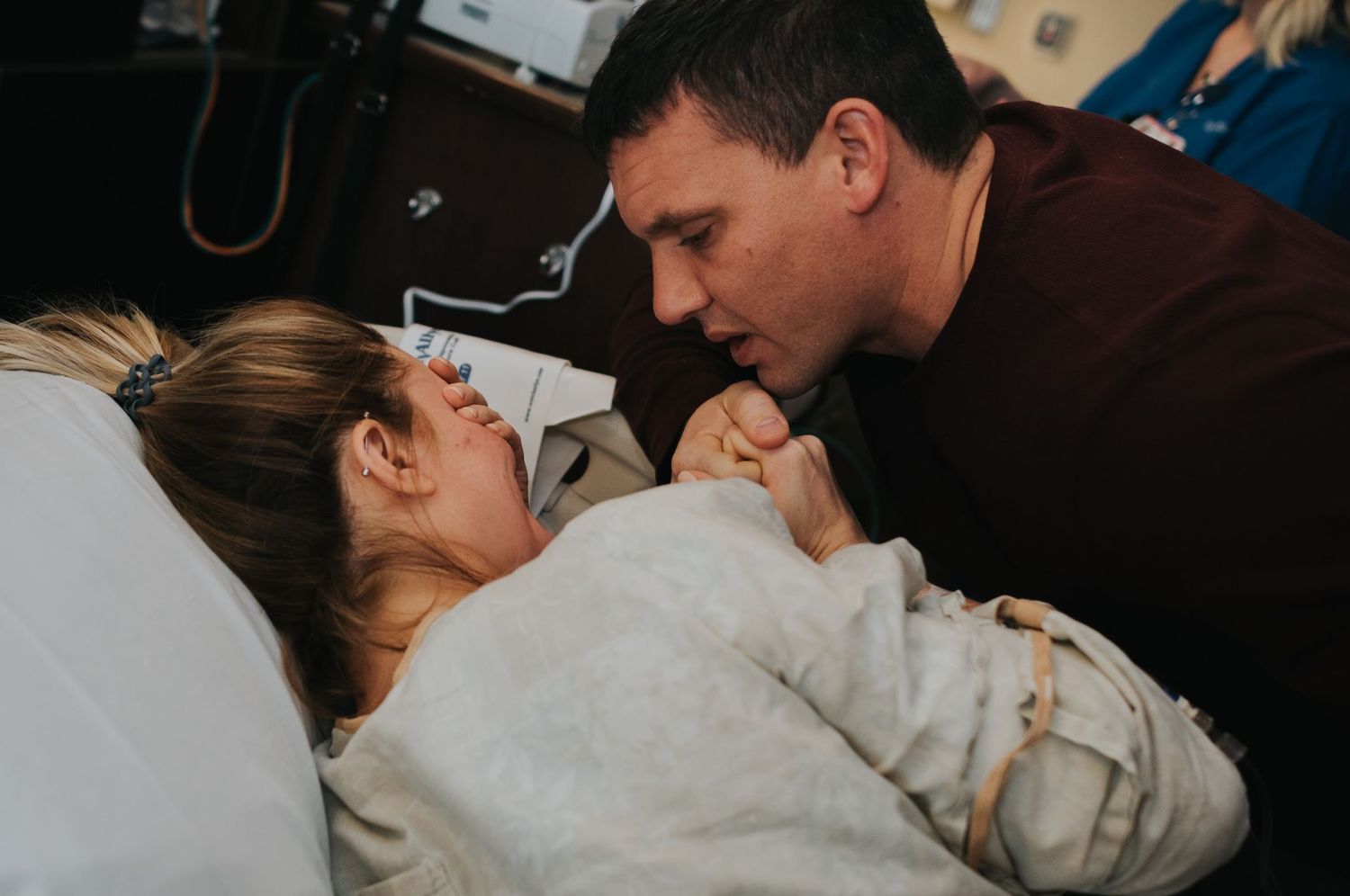 Intimate moment captured during labor showing support in hospital room.