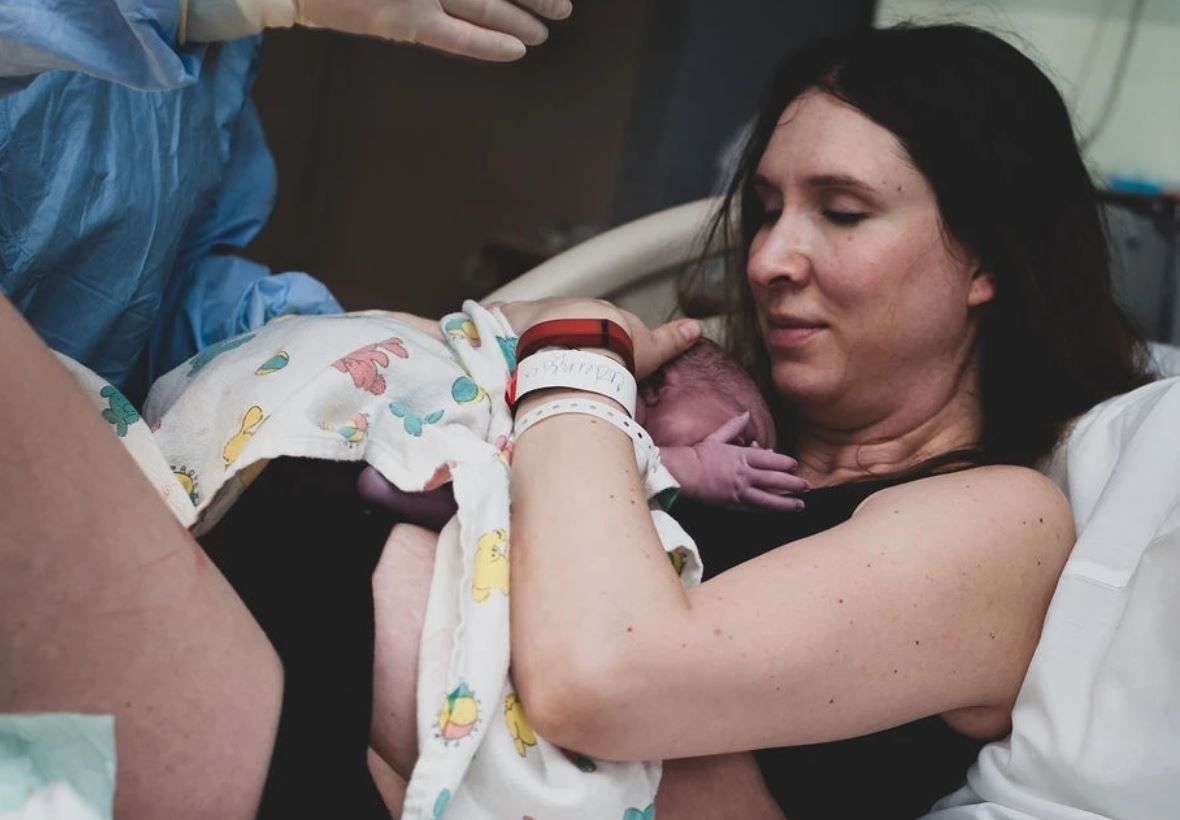 A touching skin-to-skin contact moment between mother and newborn in the delivery room.