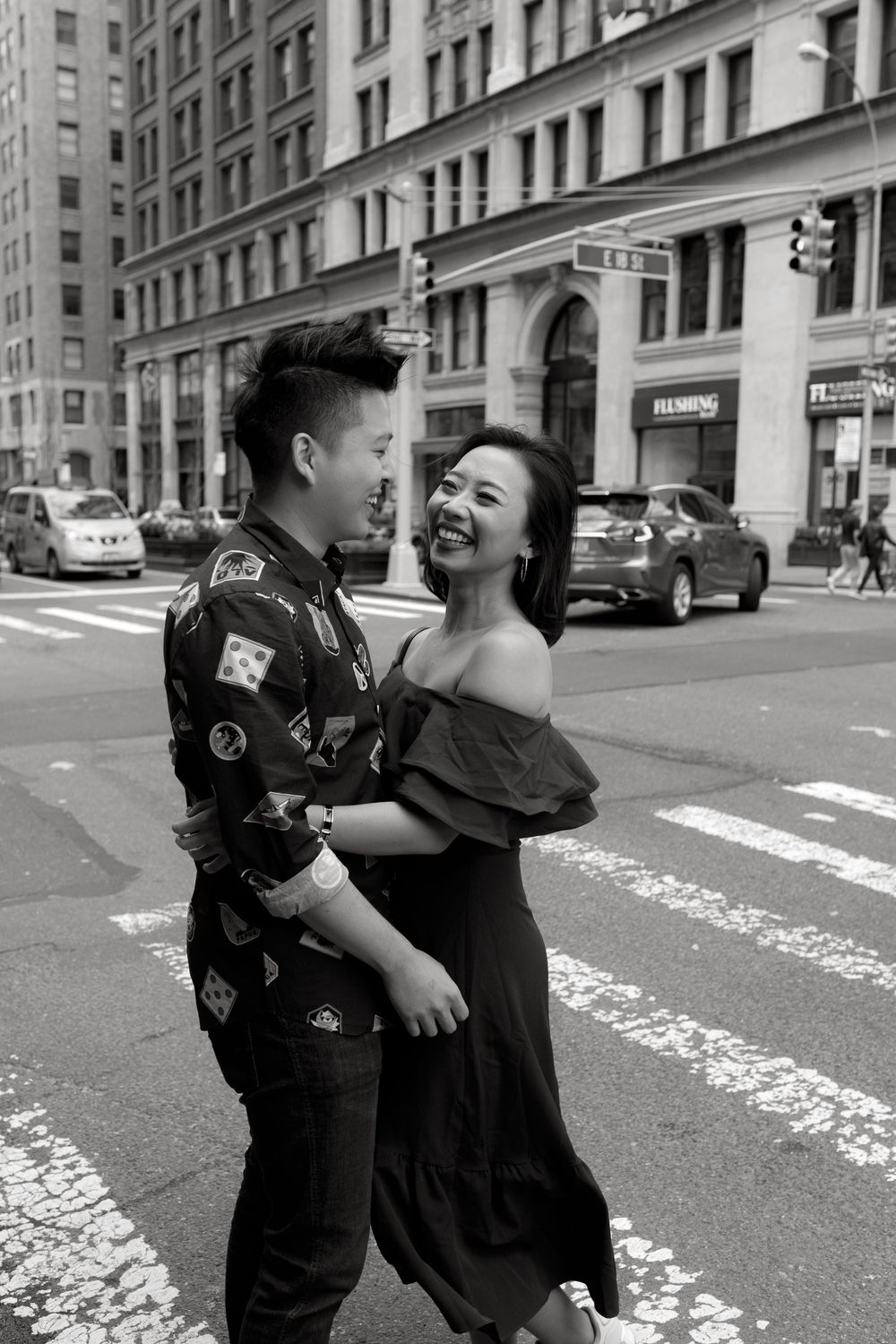 Happy Asian couple dancing together on a New York City crosswalk in black and white urban photo.