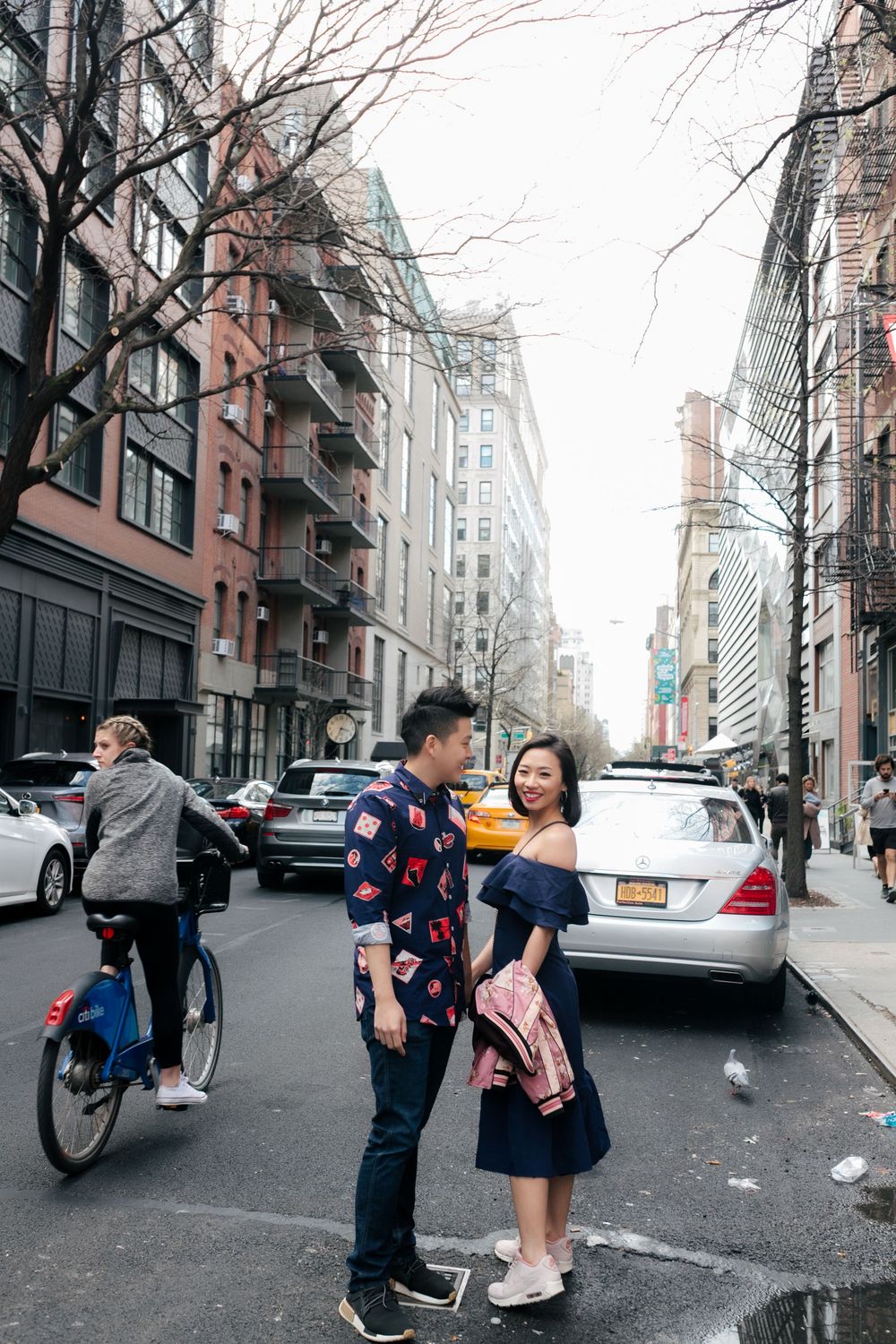 Couple sharing a romantic moment on a busy New York City street, surrounded by urban buildings and traffic.