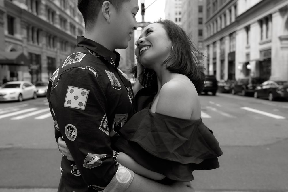 Black and white photo of a couple embracing and smiling on a city street.