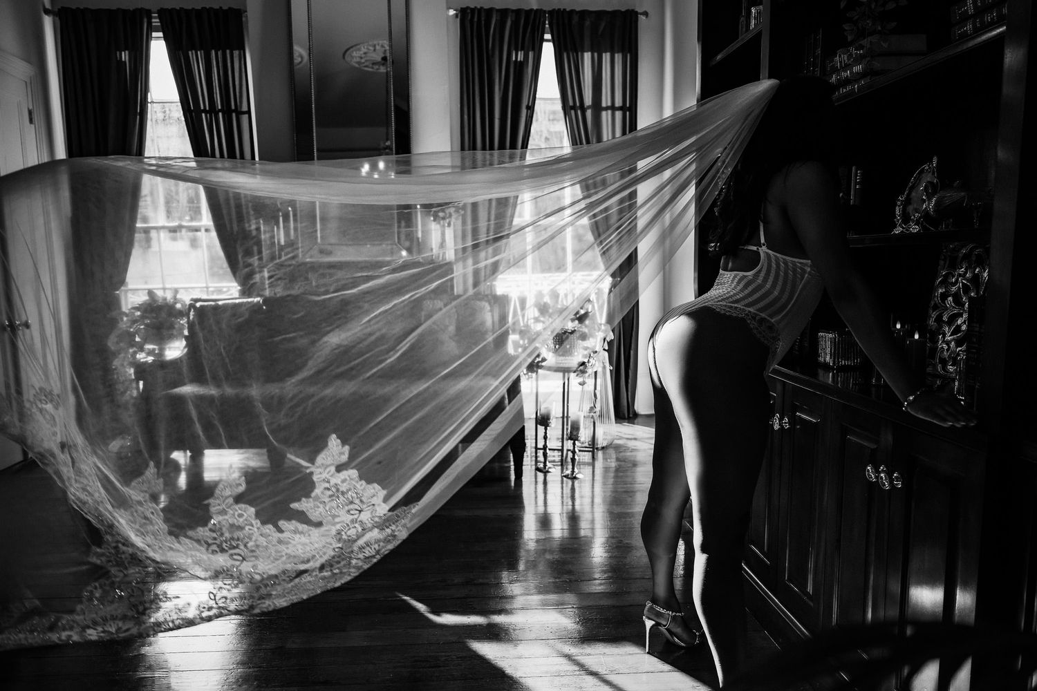 Bridal boudoir photography New Orleans - black and white boudoir photo of a woman in lingerie reflected in an ornate mirror with sheer veil.