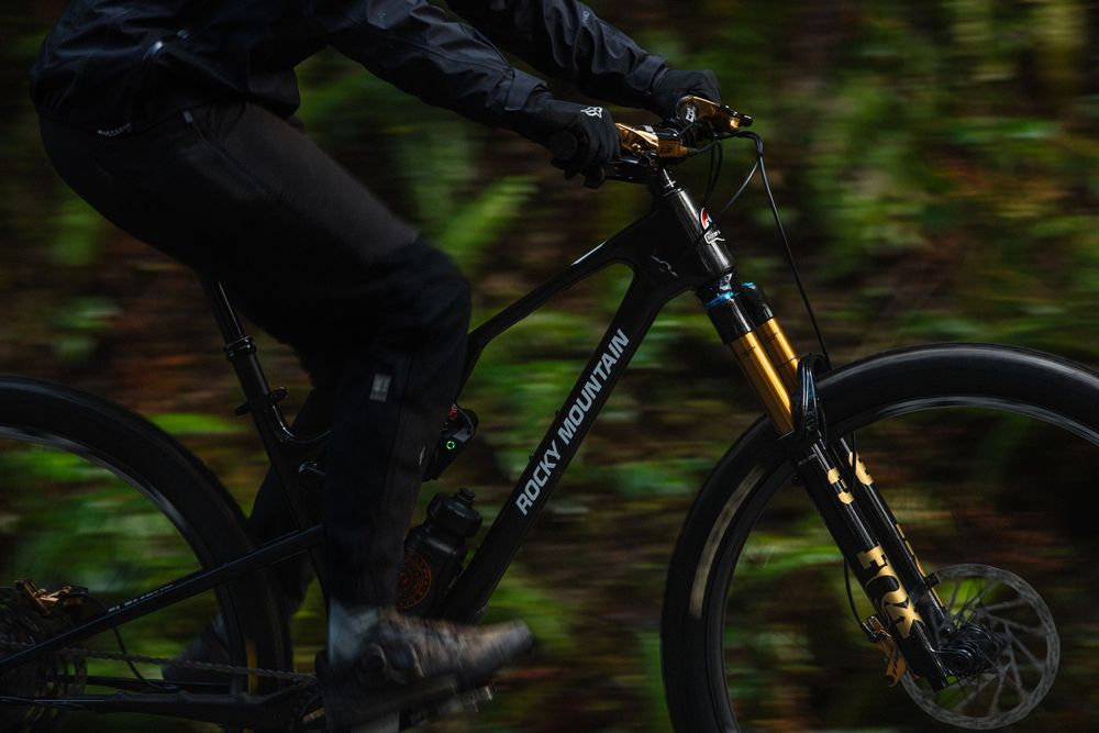 Rider on a Rocky Mountain bike speeding through a lush forest trail, motion blur capturing the thrill of mountain biking.