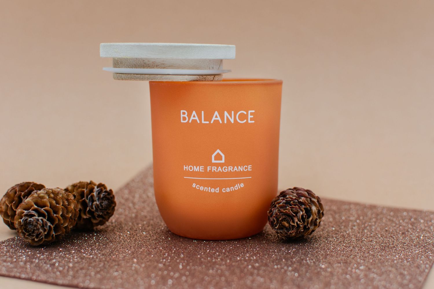 Orange candle holder with balancing lid and mini pinecones commercial product photography