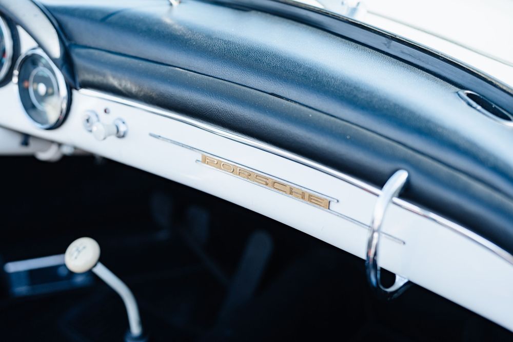Close-up of a vintage Porsche 356 dashboard with chrome trim and classic gauges in black interior.