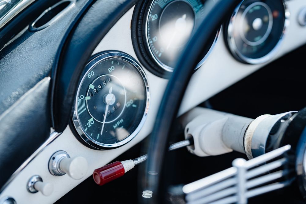Close-up of a vintage car dashboard featuring classic round gauges and retro steering wheel details.