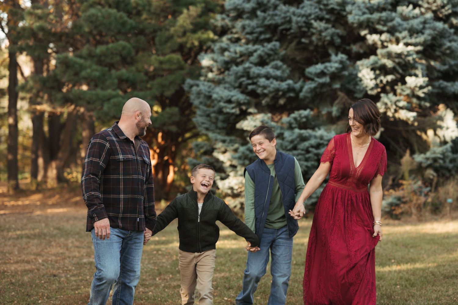 Natural outdoor family portrait with young children, genuine smiles, soft greenery and subtle film grain.