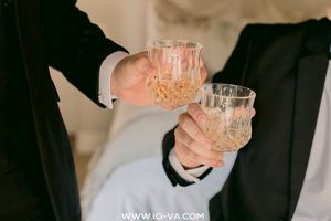 Two men in suits clinking crystal glasses filled with champagne at a formal celebration.