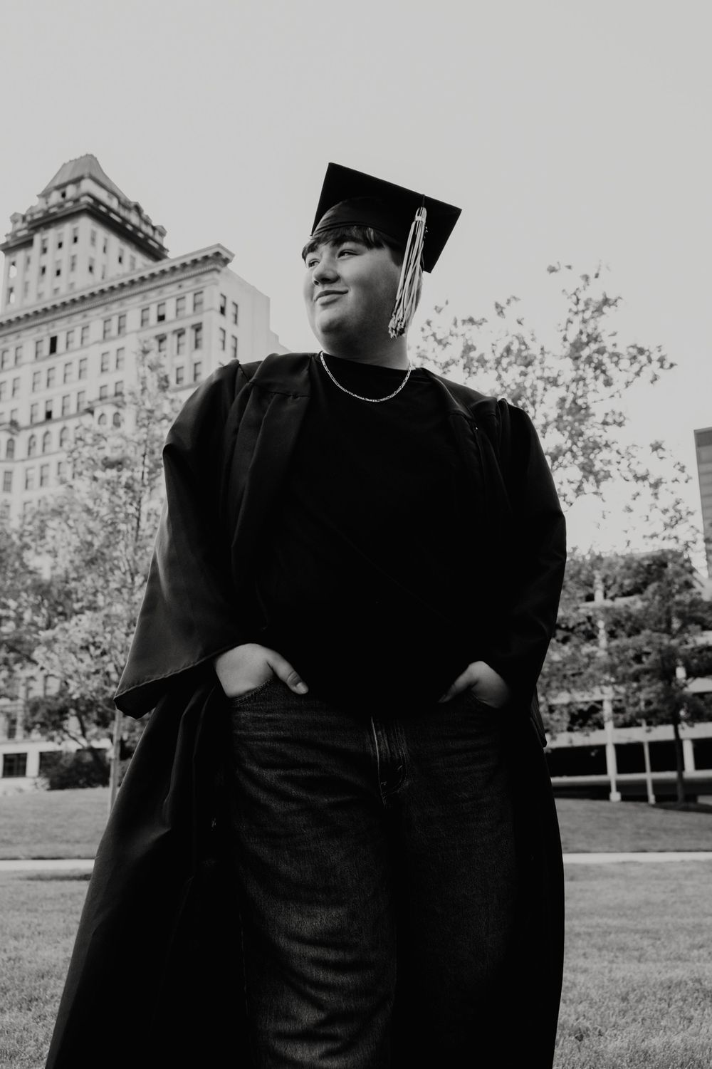 Graduate in cap and gown posing in front of university building.  - Dayton, Ohio