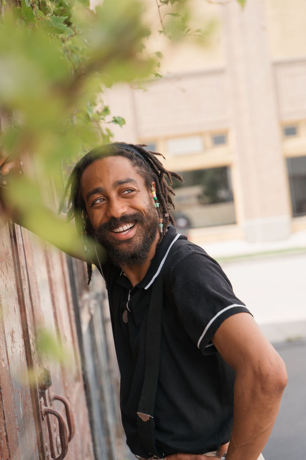 Casual outdoor portrait against wooden wall with green foliage.  - Dayton, Ohio