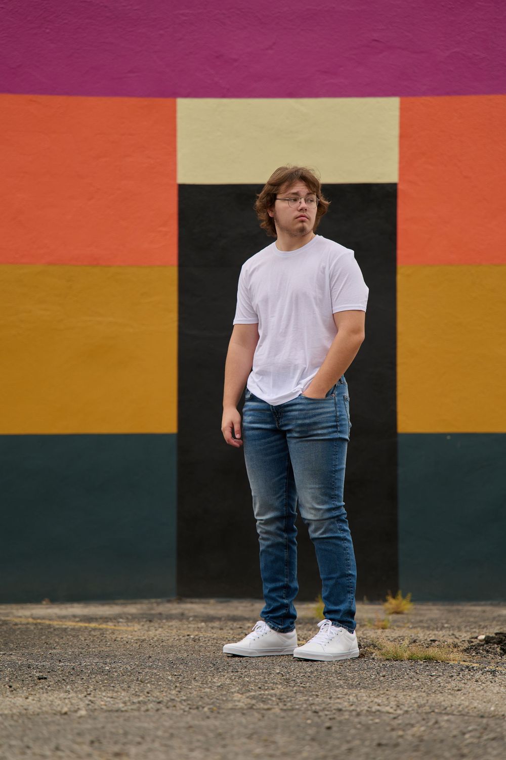 Casual high school senior portrait against colorful striped wall wearing white t-shirt and jeans. Dayton, Ohio
