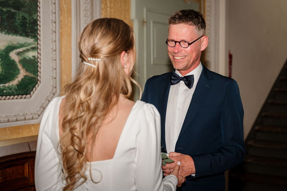 Bride and groom in tuxedo sharing a joyful moment during wedding reception indoors.