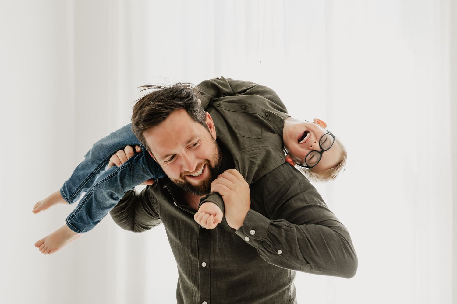 Papa und Sohn haben Spaß beim Babyfotoshooting Wien, während der Papa den Sohn quer über der Schulter trägt