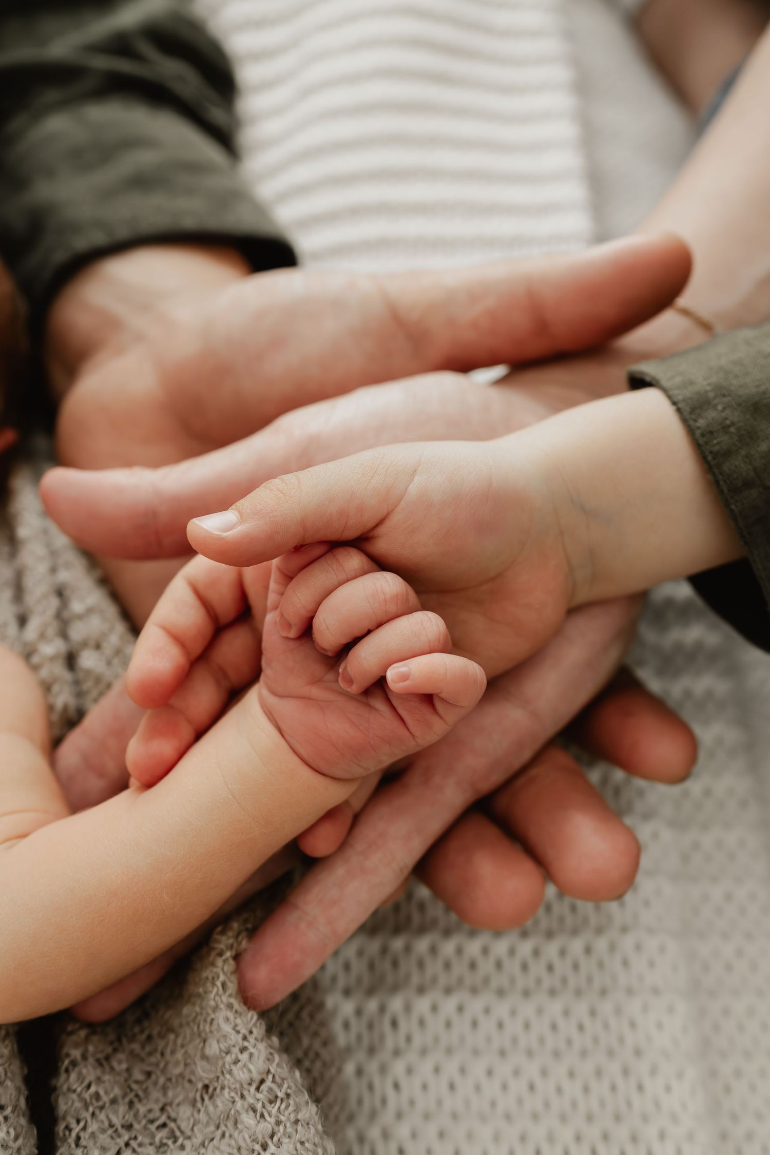 Detailfoto der Hände einer Familie beim Newbornfotoshooting Wien