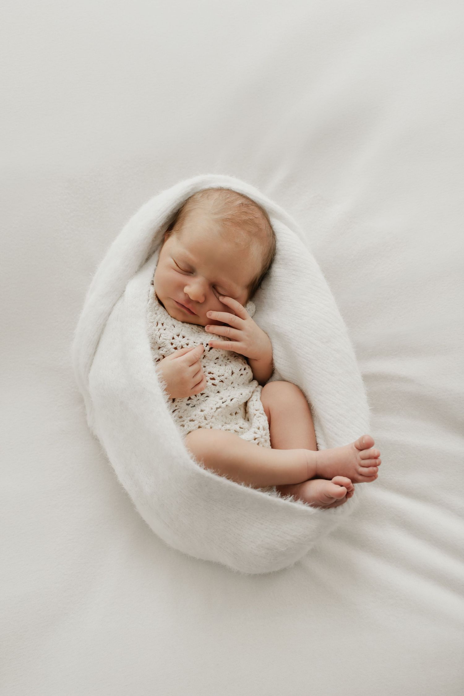 Portrait eines schlafenden Neugeborenen auf dem Beanbag umwickelt vom kuschelweichen Tuches beim Babyfotoshooting Korneuburg