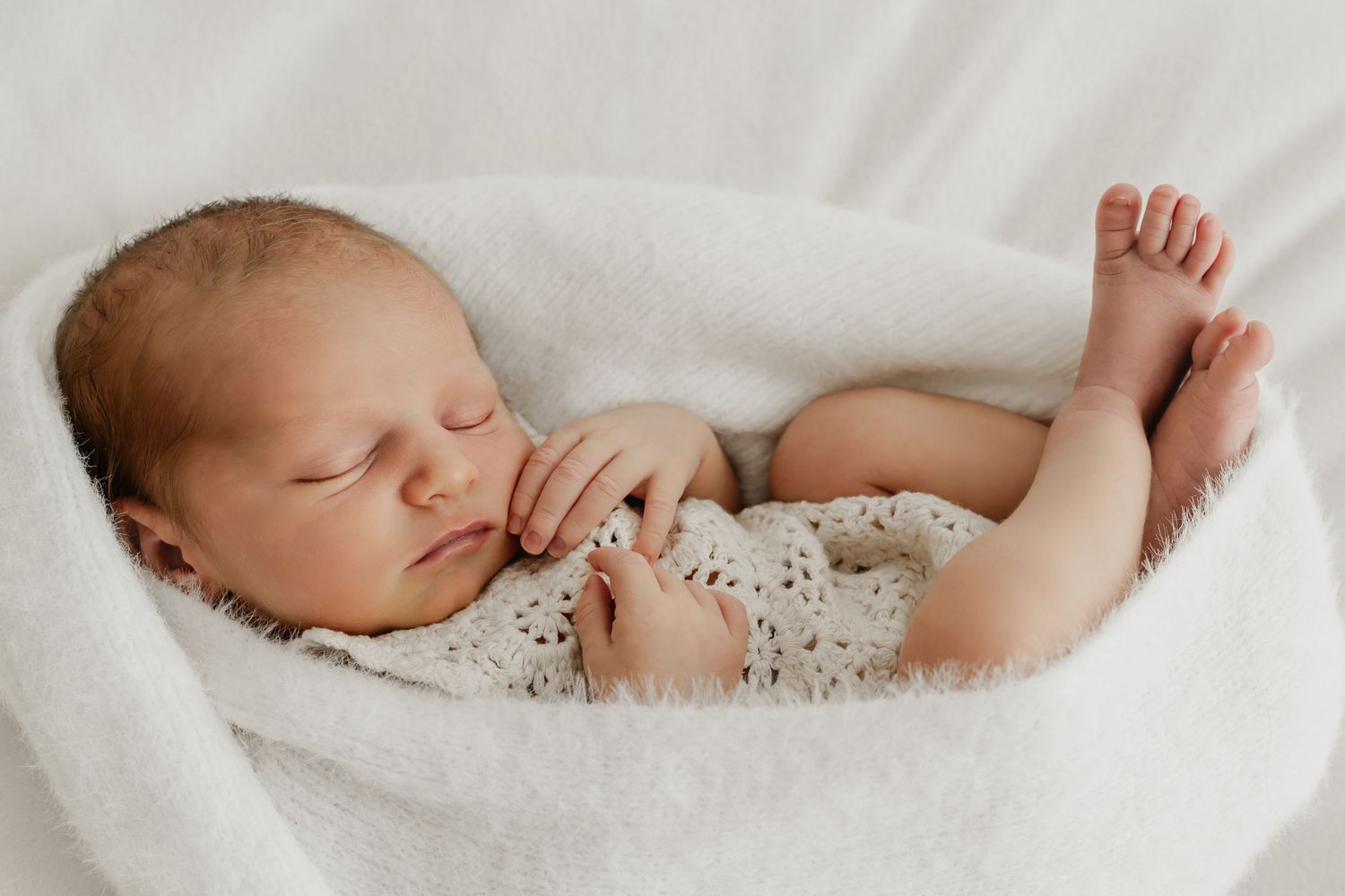 Neugeborenes Baby in der Egg-Pose im Pucktuch beim Newbornfotoshooting Stockerau