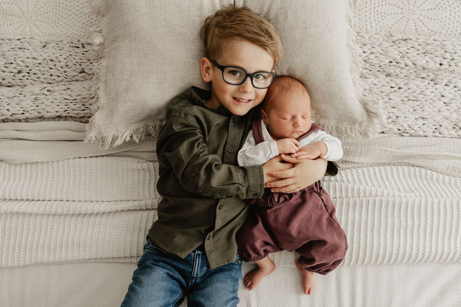 Geschwisterfoto von Bruder mit Babyschwester beim Neugeborenenfotoshooting Wien