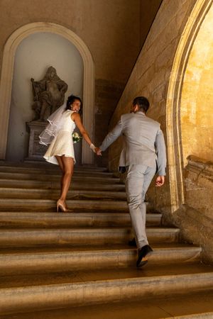 Mariés main dans la main dans un escalier provençal, photo de mariage élégante par WA Visuel.