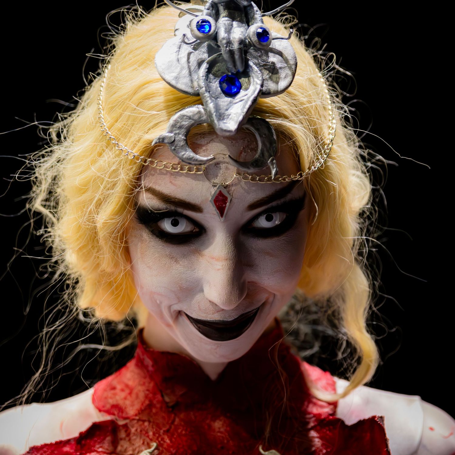 Group of cosplayers in elaborate fantasy costumes posing together against a dark background at a convention.