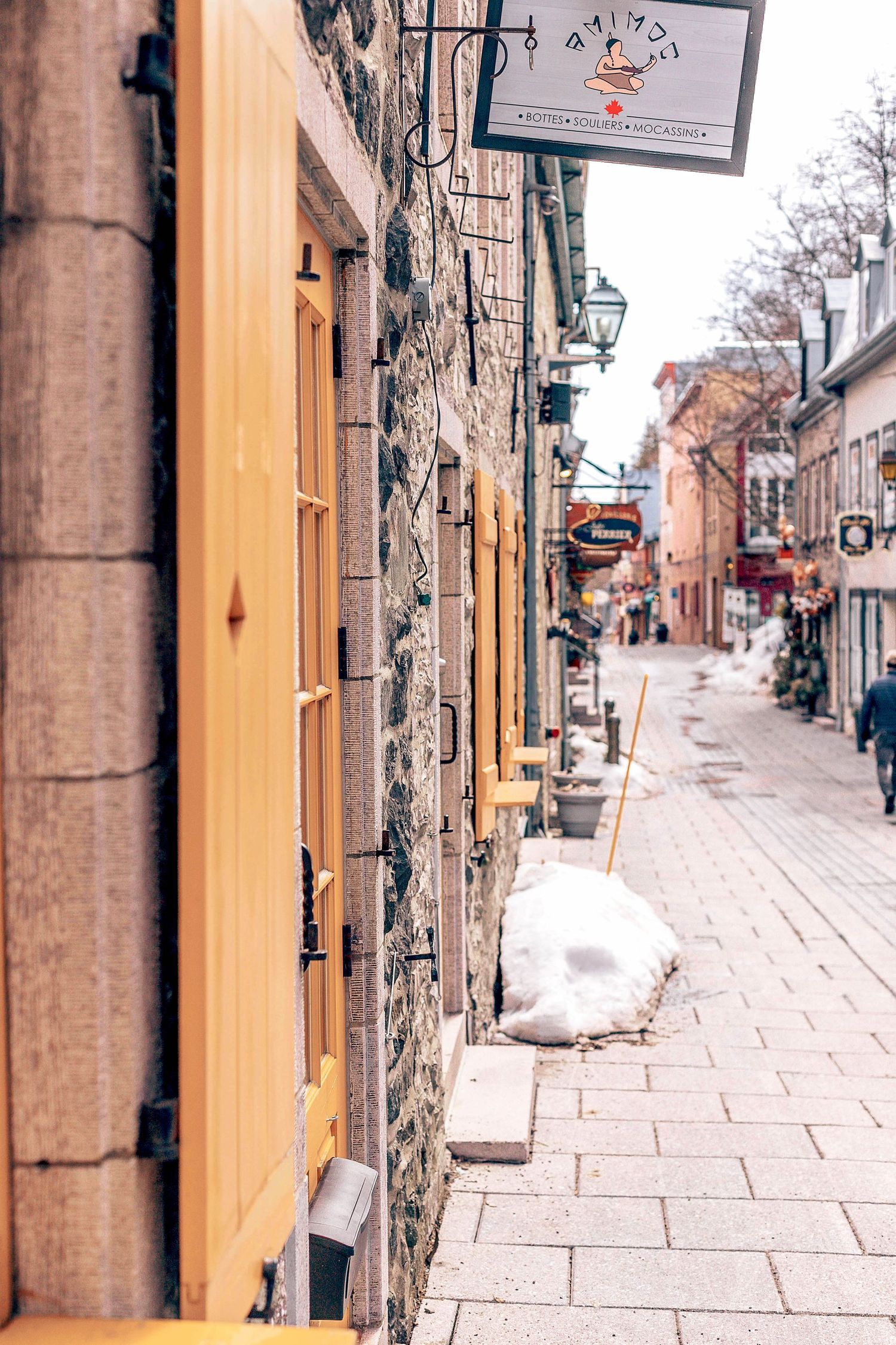 Narrow cobblestone street with yellow and stone buildings featuring traditional architecture.