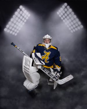 High school senior boy under stadium lights in full goalie hockey gear
