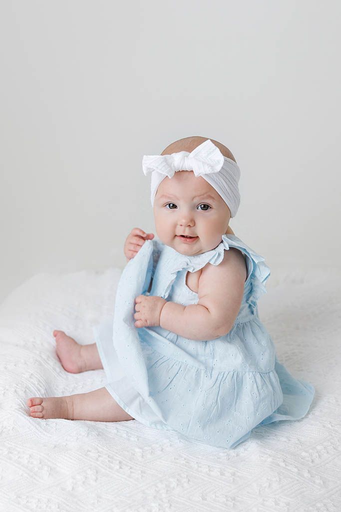 Adorable baby girl in a light blue dress and white bow headband by Temecula child photographer.