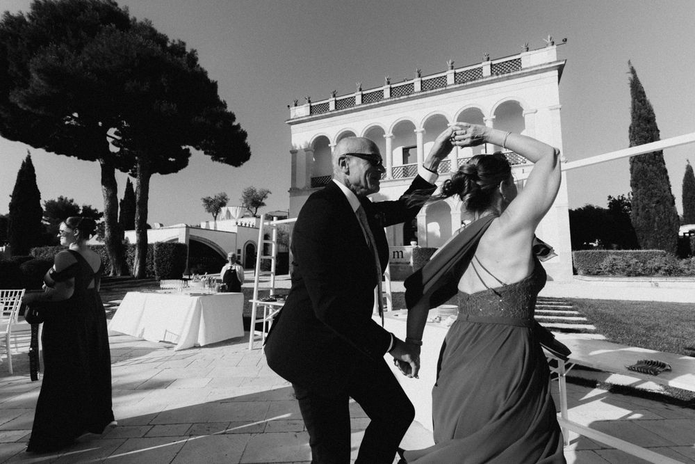 Couple dancing outdoors at elegant Italian villa wedding reception in black and white photography.