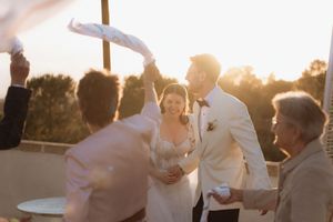 Bride and groom celebrate at golden hour wedding reception with guests waving ribbons outdoors.