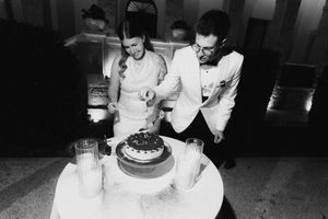Black and white photo of bride and groom cutting wedding cake at elegant reception.