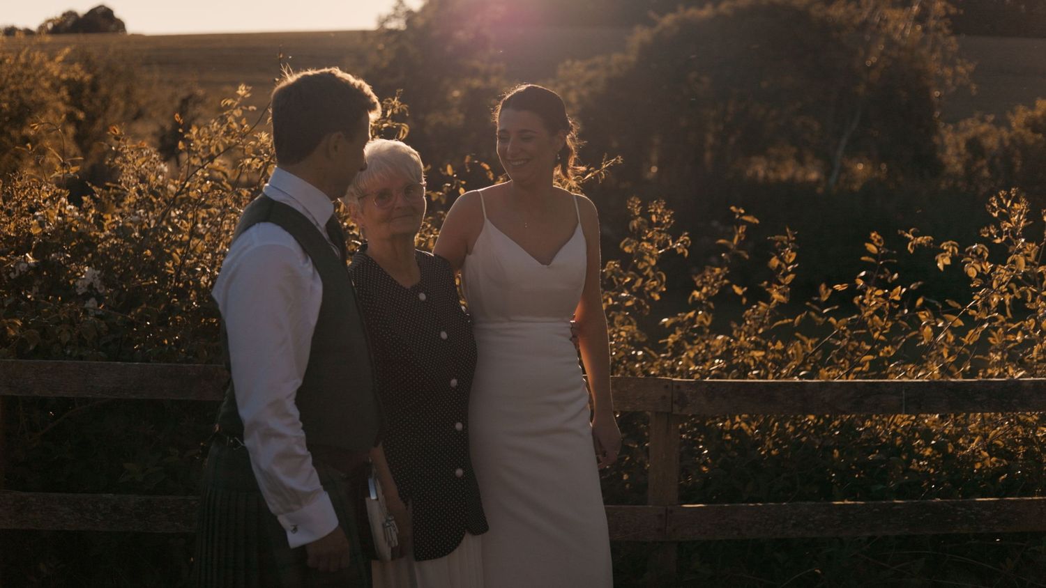 Bride and Groom farm marquee wedding in Whithorn, Dumfries & Galloway standing in golden hour light with their loved one.