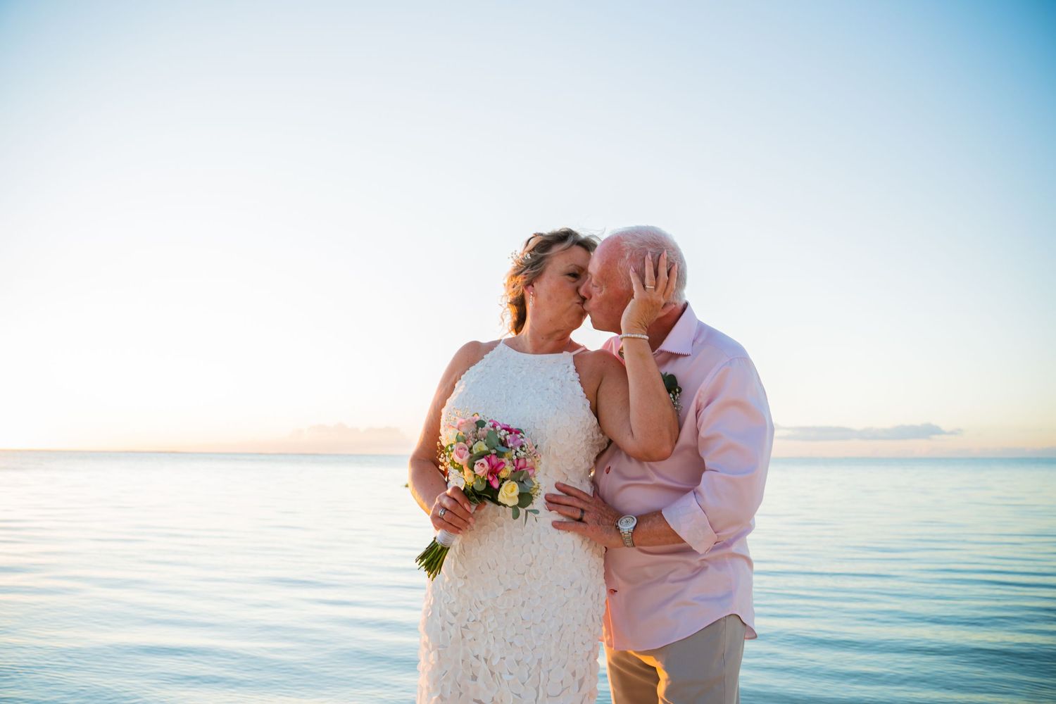Bride and groom kissing against the calm Indian Ocean during their Mauritius destination wedding