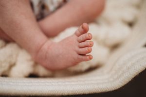 Close-up of tiny newborn baby feet resting on a soft white knit blanket.